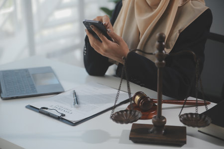 Business and lawyers discussing contract papers with brass scale on desk in office. Law, legal services, advice, justice and law concept picture with film grain effectの写真素材
