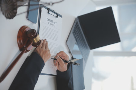 Business and lawyers discussing contract papers with brass scale on desk in office. Law, legal services, advice, justice and law concept picture with film grain effectの写真素材