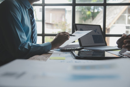 Financial analysts analyze business financial reports on a digital tablet planning investment project during a discussion at a meeting of corporate showing the results of their successful teamwork.の写真素材
