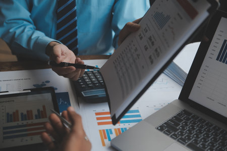 Financial analysts analyze business financial reports on a digital tablet planning investment project during a discussion at a meeting of corporate showing the results of their successful teamwork.の写真素材