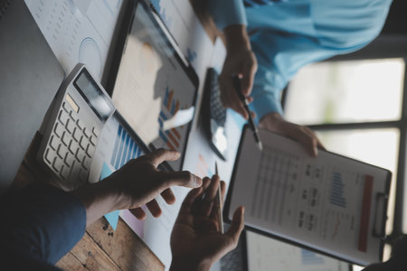 Financial analysts analyze business financial reports on a digital tablet planning investment project during a discussion at a meeting of corporate showing the results of their successful teamwork.の写真素材