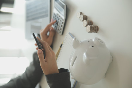 saving money and accounting concept. business man putting coin insert to jar and make acounting book for finance management to investment and saving.の写真素材