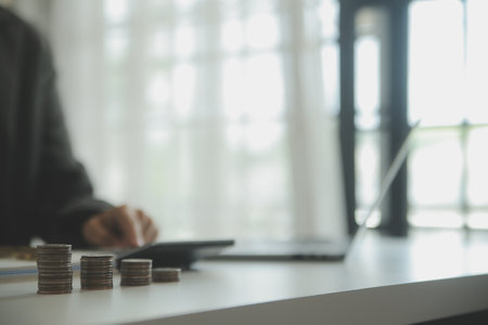 saving money and accounting concept. business man putting coin insert to jar and make acounting book for finance management to investment and saving.の写真素材
