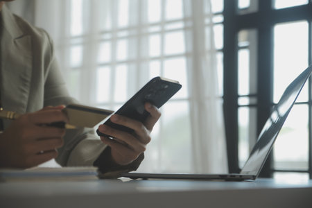 Close up woman hand using credit card and smartphone laptop for buying online shopping