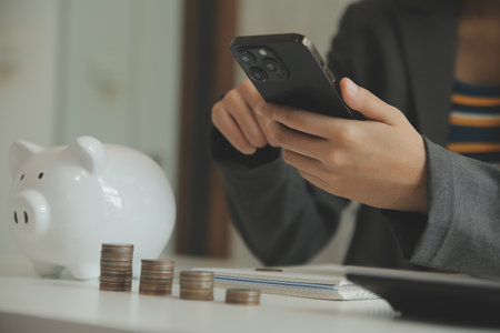 saving money and accounting concept. business man putting coin insert to jar and make acounting book for finance management to investment and saving.の写真素材
