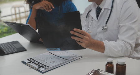 Focused mature male doctor and female nurse look at tablet screen discuss anamnesis together....