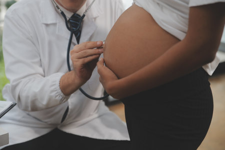 Female doctor is checking pregnant woman with stethoscope. Concept caring for pregnant womanの写真素材