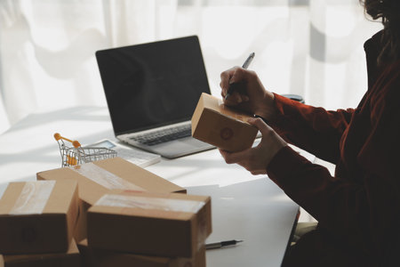 Portrait young attractive hipster asia female owner startup look at camera work happy with box at home prepare parcel delivery in sme supply chain, procurement, omnichannel ecommerce online concept.の写真素材