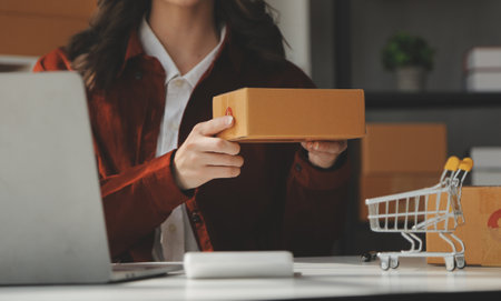 Portrait young attractive hipster asia female owner startup look at camera work happy with box at home prepare parcel delivery in sme supply chain, procurement, omnichannel ecommerce online concept.の写真素材