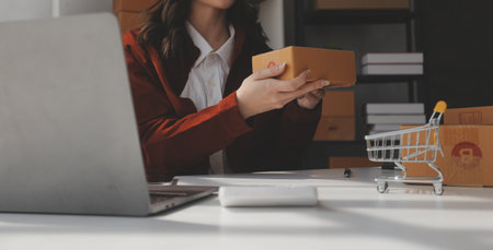 Portrait young attractive hipster asia female owner startup look at camera work happy with box at home prepare parcel delivery in sme supply chain, procurement, omnichannel ecommerce online concept.の写真素材