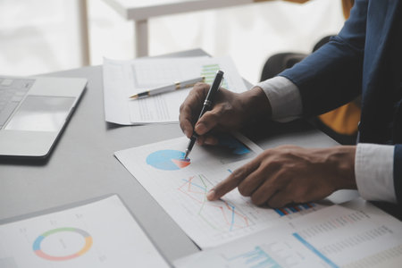Financial analysts analyze business financial reports on a digital tablet planning investment project during a discussion at a meeting of corporate showing the results of their successful teamwork.の写真素材
