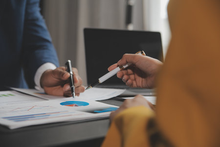 Financial analysts analyze business financial reports on a digital tablet planning investment project during a discussion at a meeting of corporate showing the results of their successful teamwork.の写真素材