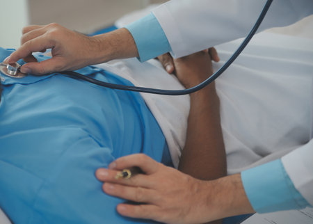 Close up of doctor sitting on bedside of male patient in hospital