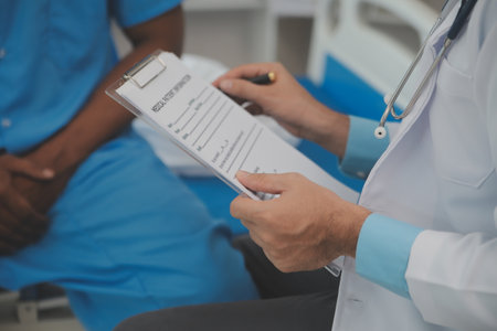 Close up of doctor sitting on bedside of male patient in hospital