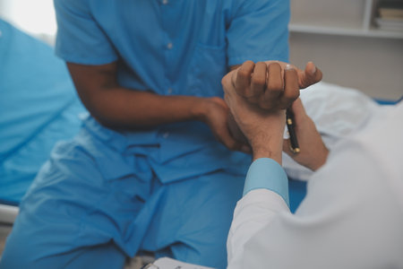 Close up of doctor sitting on bedside of male patient in hospitalの写真素材