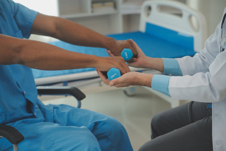 Physiotherapist man giving exercise with dumbbell treatment About Arm and Shoulder of athlete male patient Physical therapy conceptの写真素材