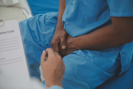 Close up of doctor sitting on bedside of male patient in hospitalの写真素材
