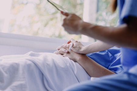 Professional female doctor smiles and shows positive examination results to young, joyful man. Handsome, happy guy with glasses at doctor's appointment in modern office of medical institution.の写真素材