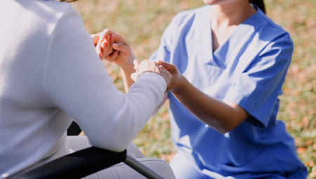 Asian young woman nurse at nursing home take care disabled senior man. Caregiver doctor serve physical therapy for older elderly patient to exercise and practice walking on walker or cane at backyard.の写真素材