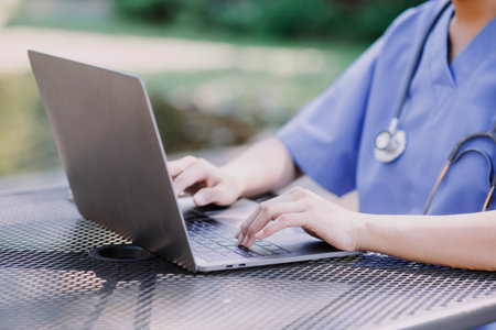 Female Doctor Wearing Scrubs In Hospital Corridor Using Digital Tabletの写真素材