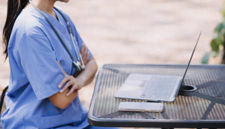 Female Doctor Wearing Scrubs In Hospital Corridor Using Digital Tabletの写真素材