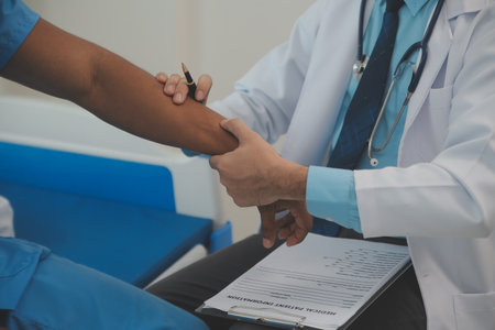Close up of doctor sitting on bedside of male patient in hospitalの写真素材