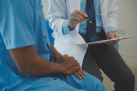 Close up of doctor sitting on bedside of male patient in hospitalの写真素材