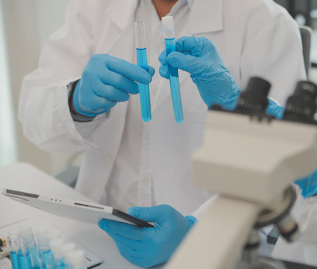 Health care researchers working in life science laboratory. Young female research scientist and senior male supervisor preparing and analyzing microscope slides in research lab.の写真素材