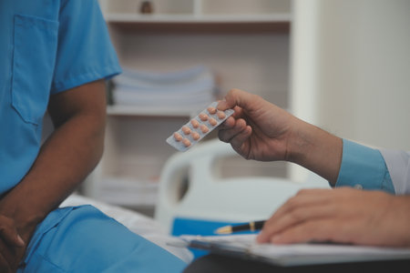 Close up of doctor sitting on bedside of male patient in hospitalの写真素材