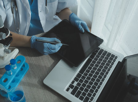 Young scientists conducting research investigations in a medical laboratory, a researcher in the foreground is using a microscopeの写真素材