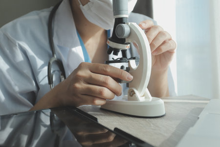 Young scientists conducting research investigations in a medical laboratory, a researcher in the foreground is using a microscopeの写真素材