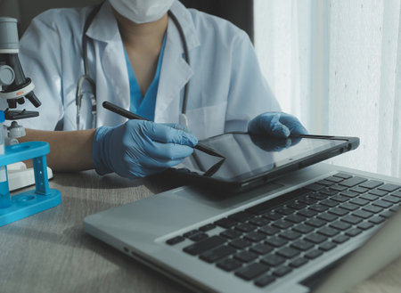 Young scientists conducting research investigations in a medical laboratory, a researcher in the foreground is using a microscopeの写真素材