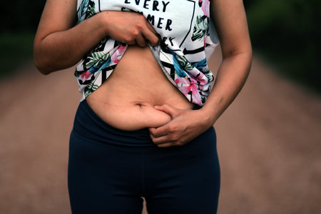 Women body fat belly. Obese woman hand holding excessive belly fat. diet lifestyle concept to reduce belly and shape up healthy stomach muscle.の写真素材