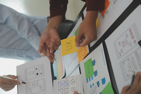 Close up ux developer and ui designer brainstorming about mobile app interface wireframe design on table with customer breif and color code at modern office.Creative digital development agencyの写真素材