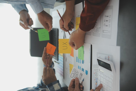 Close up ux developer and ui designer brainstorming about mobile app interface wireframe design on table with customer breif and color code at modern office.Creative digital development agencyの写真素材
