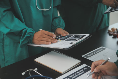 Multiracial team of doctors discussing a patient standing grouped in the foyer looking at a tablet computer, close up viewの写真素材
