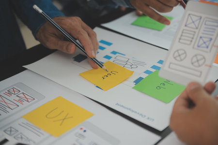Close up ux developer and ui designer brainstorming about mobile app interface wireframe design on...