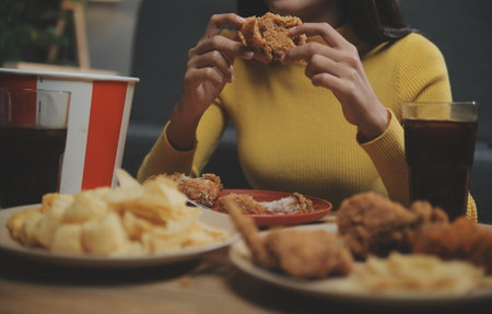 fat woman bite piece of pizza,overweight female is eating fast foods,asian girl is hungryの写真素材
