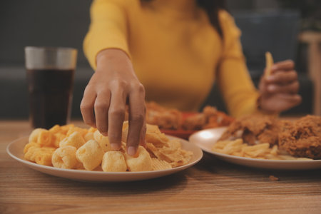 fat woman bite piece of pizza,overweight female is eating fast foods,asian girl is hungryの写真素材