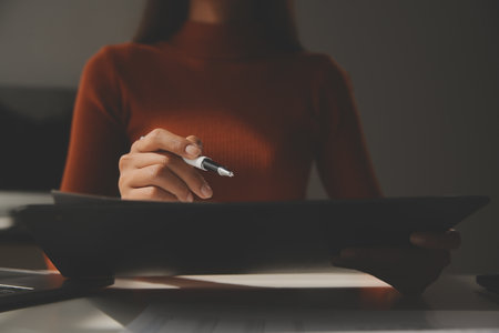 Asian Businesswoman Using laptop computer and working at office with calculator document on desk, doing planning analyzing the financial report, business plan investment, finance analysis concept.の写真素材