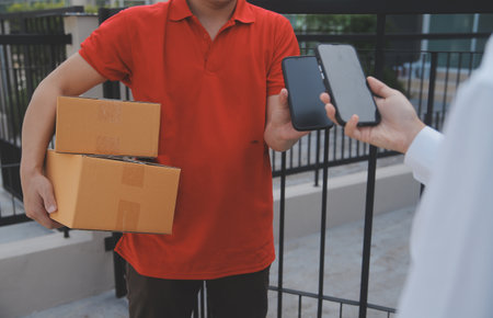 Asian Woman Receiving Product from delivery man at Home, Young Owner Woman Order Product from Smartphone Application, Woman with Online Business or SME Concept.の写真素材