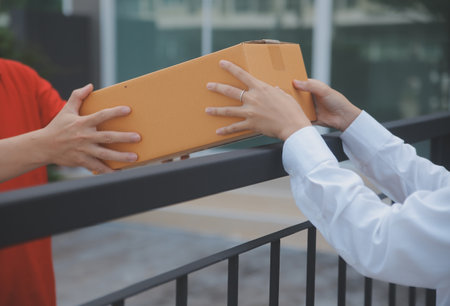Asian Woman Receiving Product from delivery man at Home, Young Owner Woman Order Product from Smartphone Application, Woman with Online Business or SME Concept.の写真素材