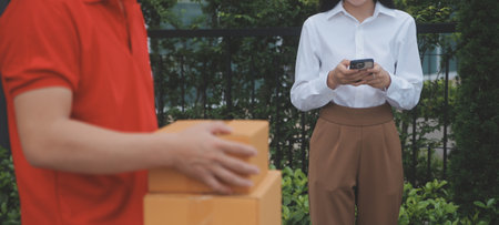 Asian Woman Receiving Product from delivery man at Home, Young Owner Woman Order Product from Smartphone Application, Woman with Online Business or SME Concept.の写真素材