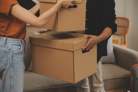 Beautiful young couple in love having fun unpacking things from cardboard boxes while moving in...