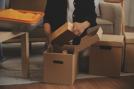 Beautiful young couple in love having fun unpacking things from cardboard boxes while moving in...