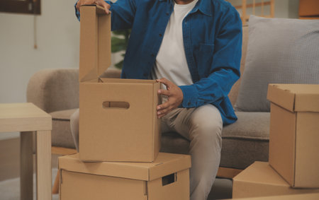 Beautiful young couple in love having fun unpacking things from cardboard boxes while moving in together in their new apartmentの写真素材
