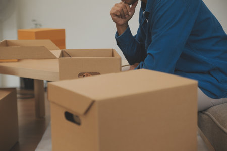 Beautiful young couple in love having fun unpacking things from cardboard boxes while moving in together in their new apartmentの写真素材