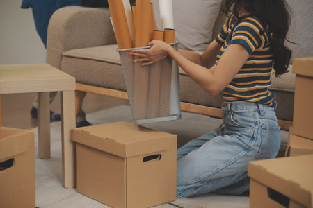 Beautiful young couple in love having fun unpacking things from cardboard boxes while moving in...
