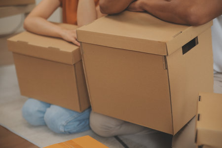 Beautiful young couple in love having fun unpacking things from cardboard boxes while moving in together in their new apartmentの写真素材