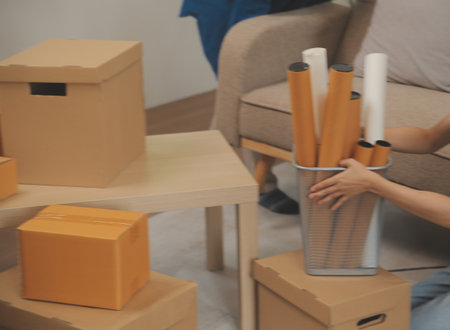 Beautiful young couple in love having fun unpacking things from cardboard boxes while moving in...